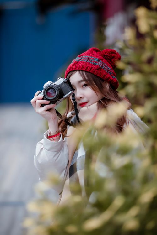 Free Stylish woman capturing moments outdoors with a vintage camera. Stock Photo