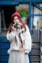 Selective Focus Photo of a Woman Wearing a Scarf Holding a Camera