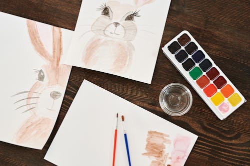 Paintings and Watercolor Paints on Table