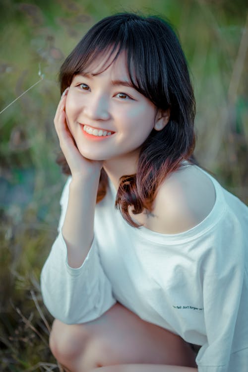 Close-Up Photo of a Woman Smiling while Holding Her Cheek