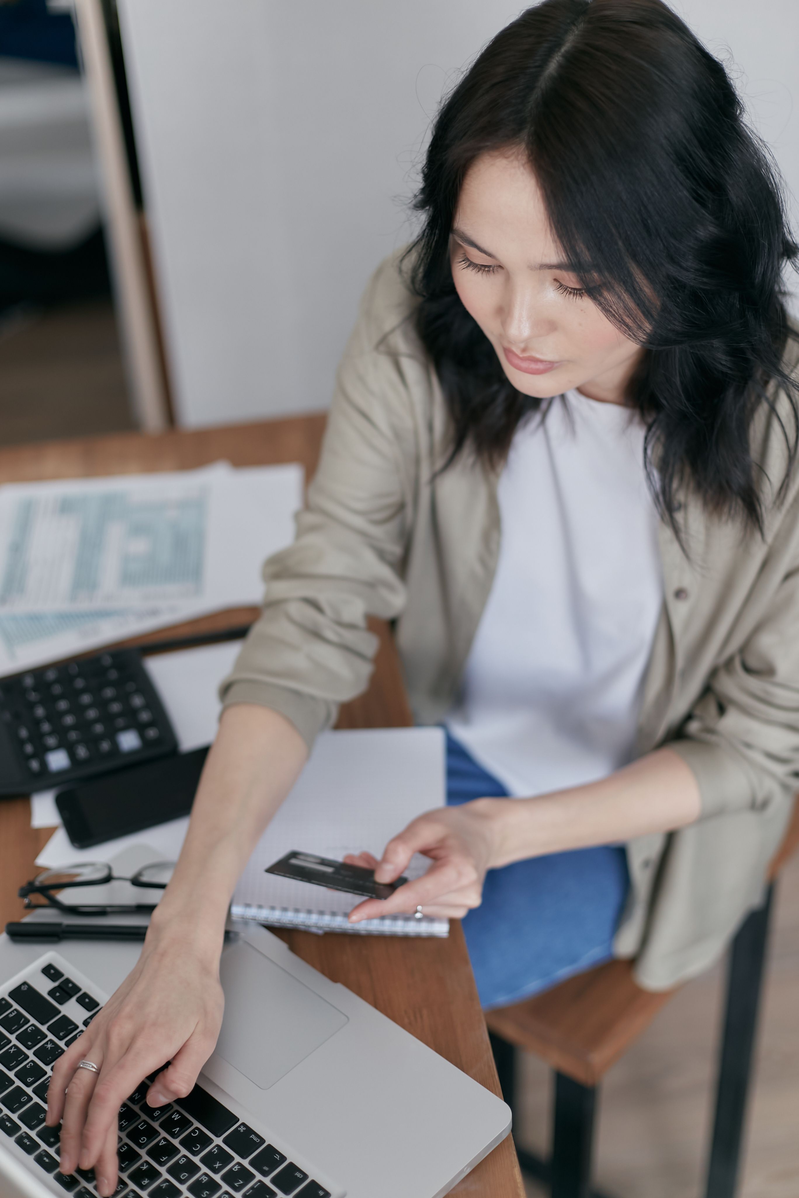 a woman holding a credit card while reviewing paperwork.