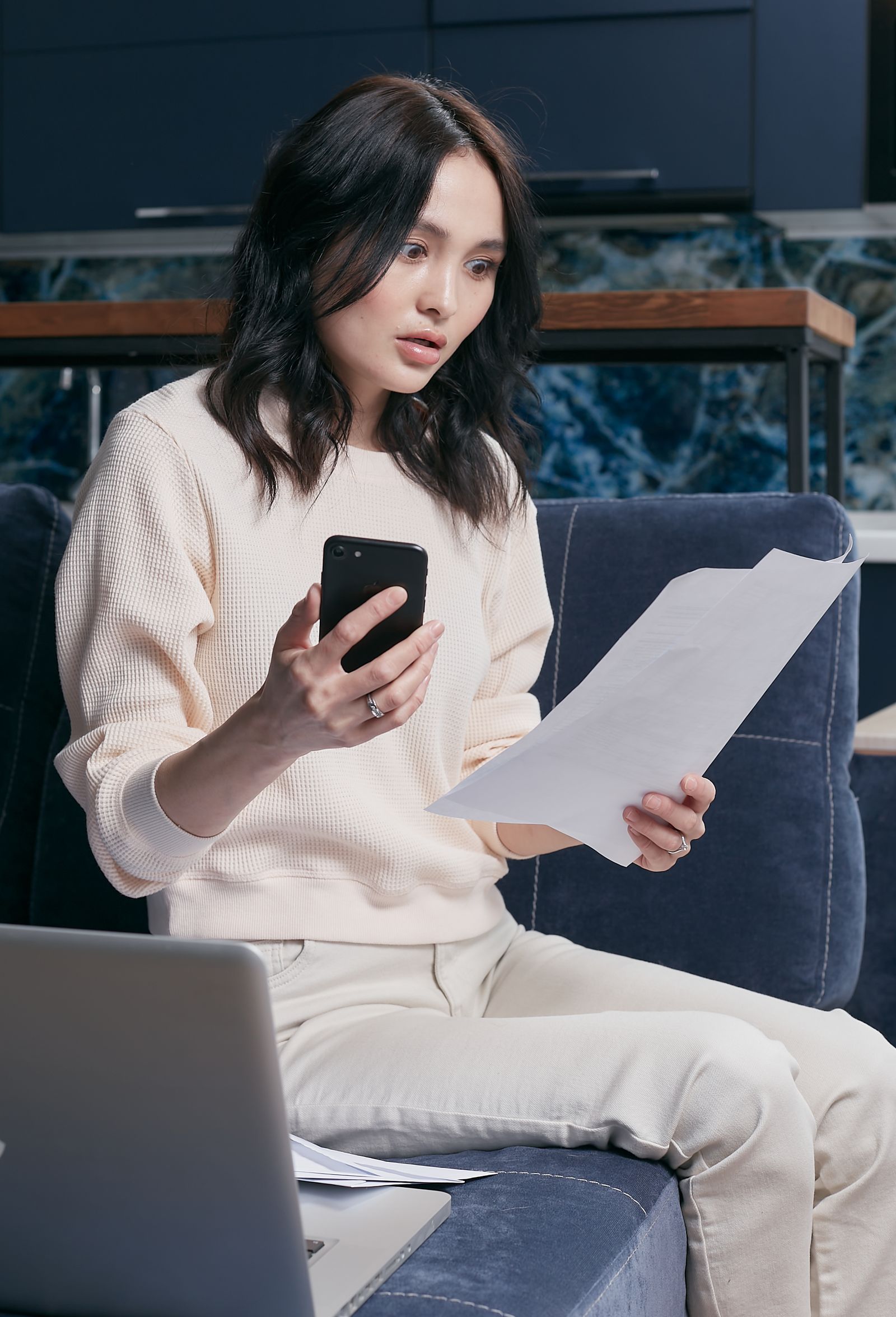 Borrower checking a smartphone and laptop while waiting for a financial transaction
