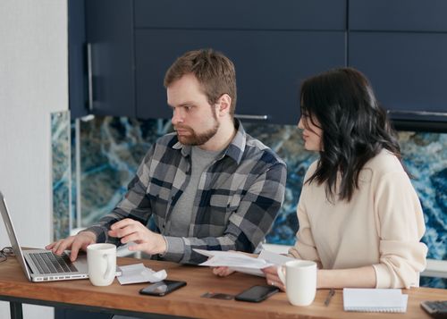 Free A couple working together on a laptop managing finances at home, showcasing teamwork and concentration. Stock Photo