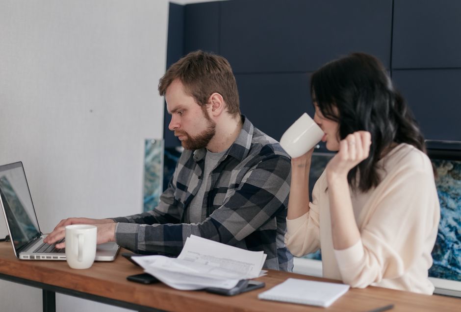 Una pareja en casa, centrada en el presupuesto y las finanzas con una laptop.