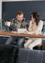 A Couple Sitting Near the Wooden Table while Looking at the Document in Shocked Emotion