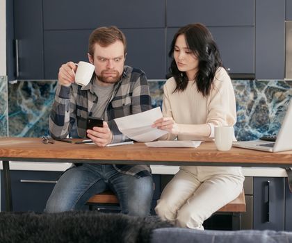A Man Looking at the Paper while Holding a Coffee and Phone