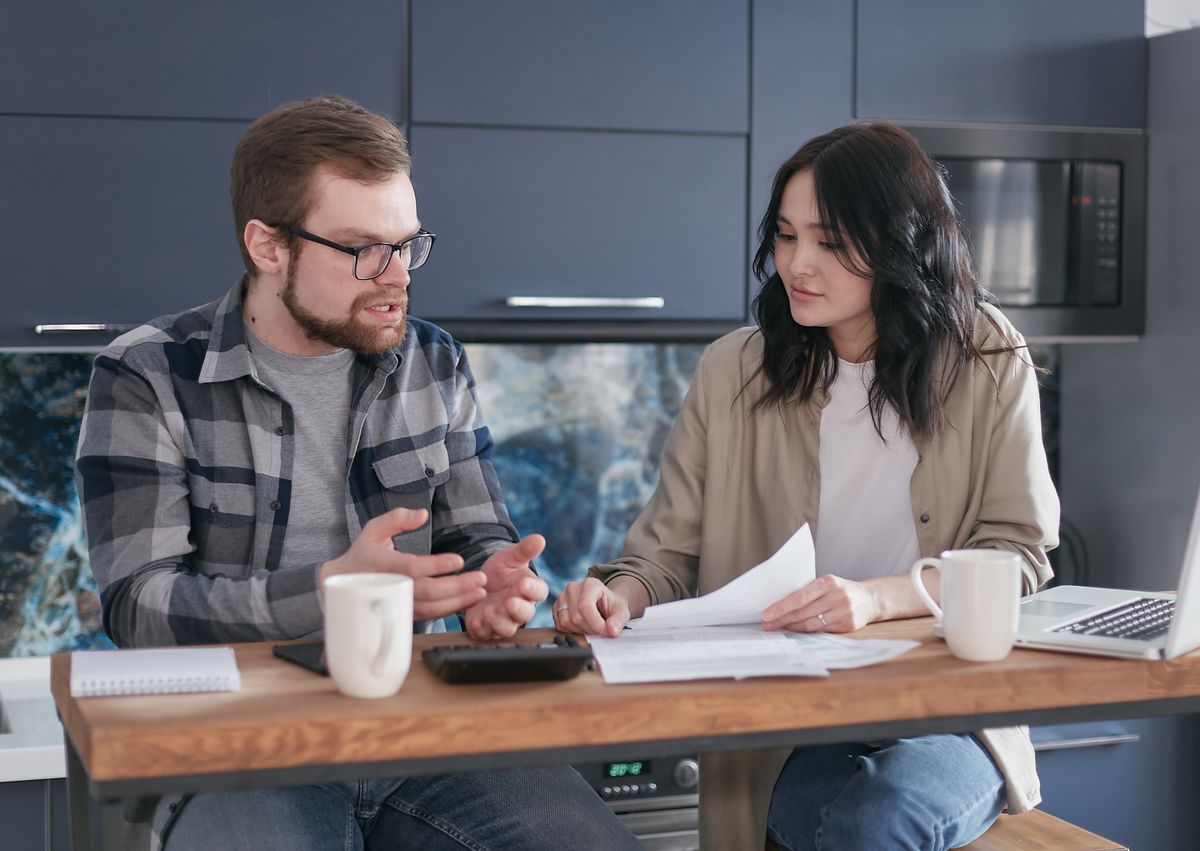 Couple comparing bills and loan options at a wooden table
