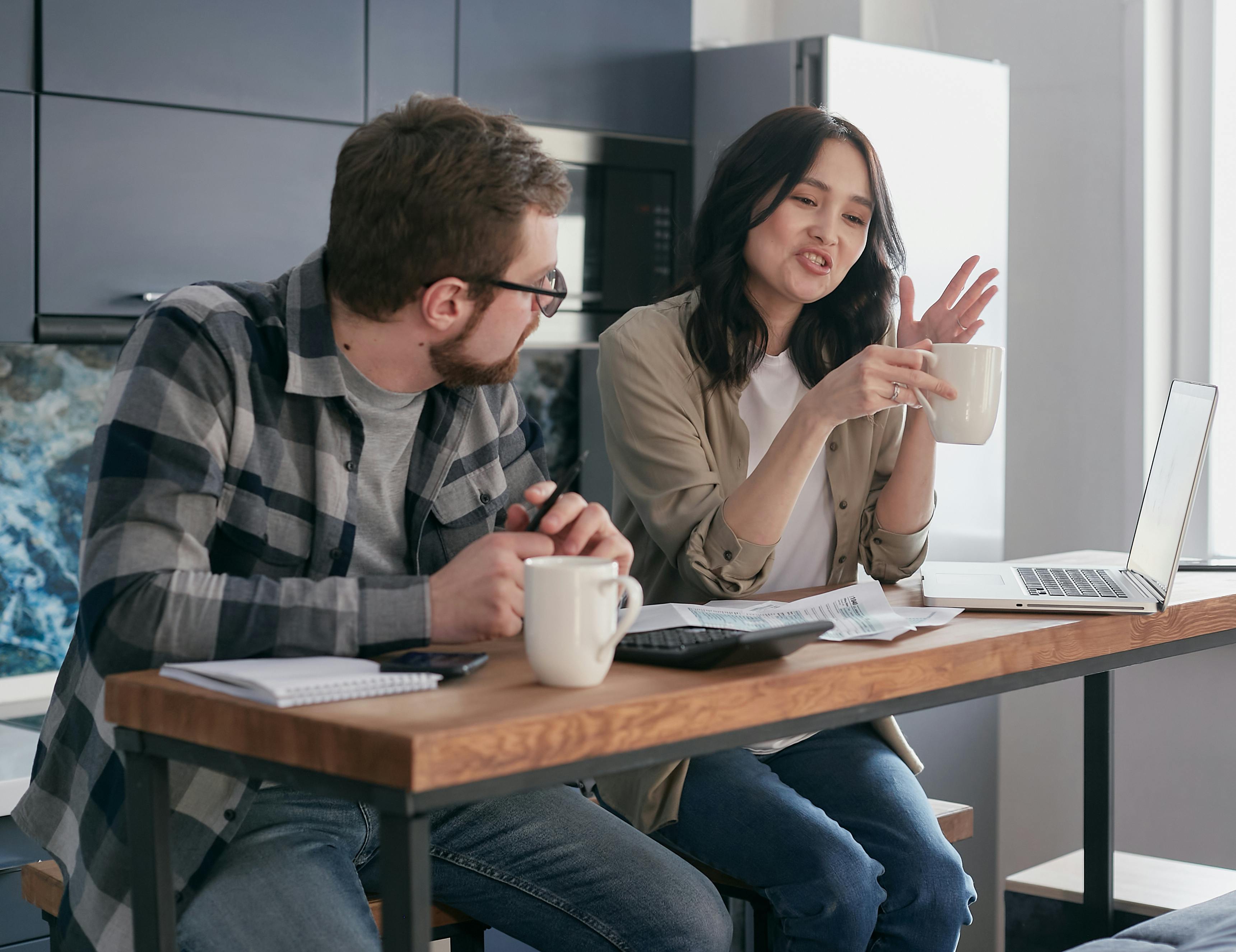 a man looking at his partner talking while holding a cup of coffee