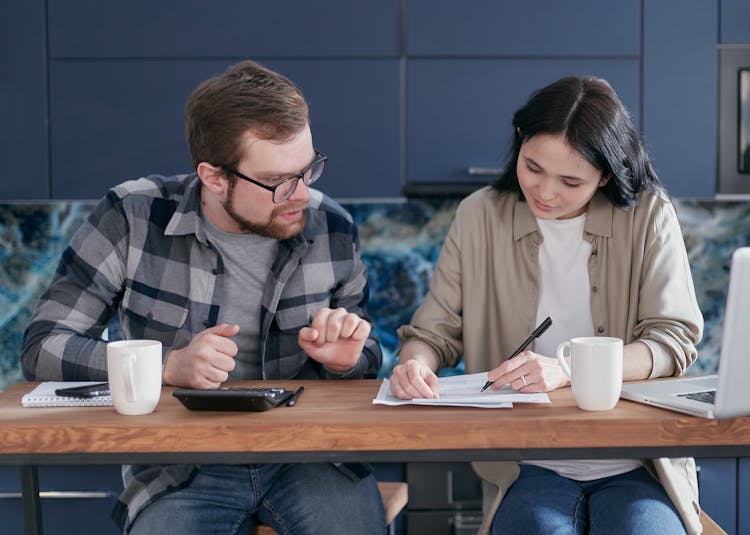 Man And Woman Sitting At Table With Documents 