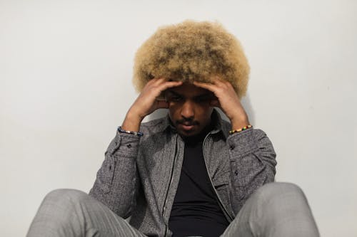 A Man in Gray Jacket Leaning on the Wall while Thinking