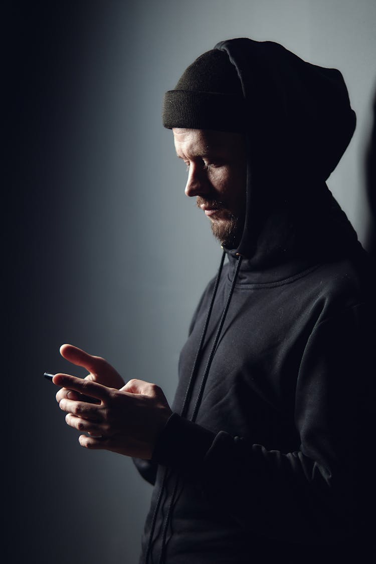 Man In Black Hoodie Using Smartphone