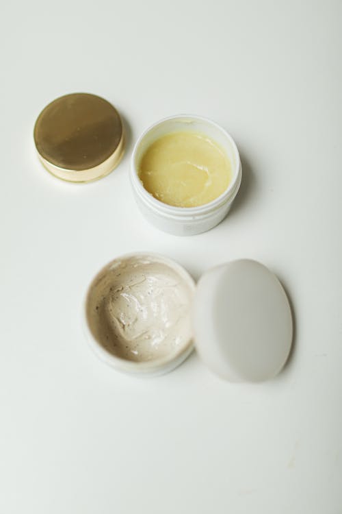 Opened Containers with Creams on White Background 