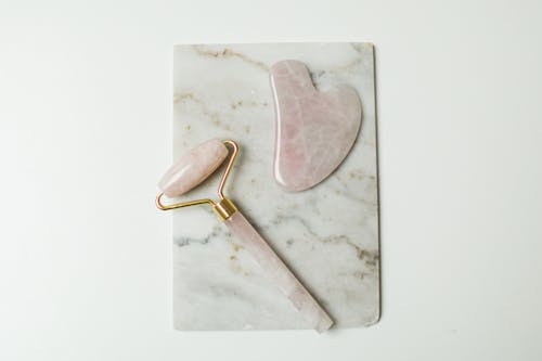A Flatlay of Face Roller and Gua Sha on a Marble