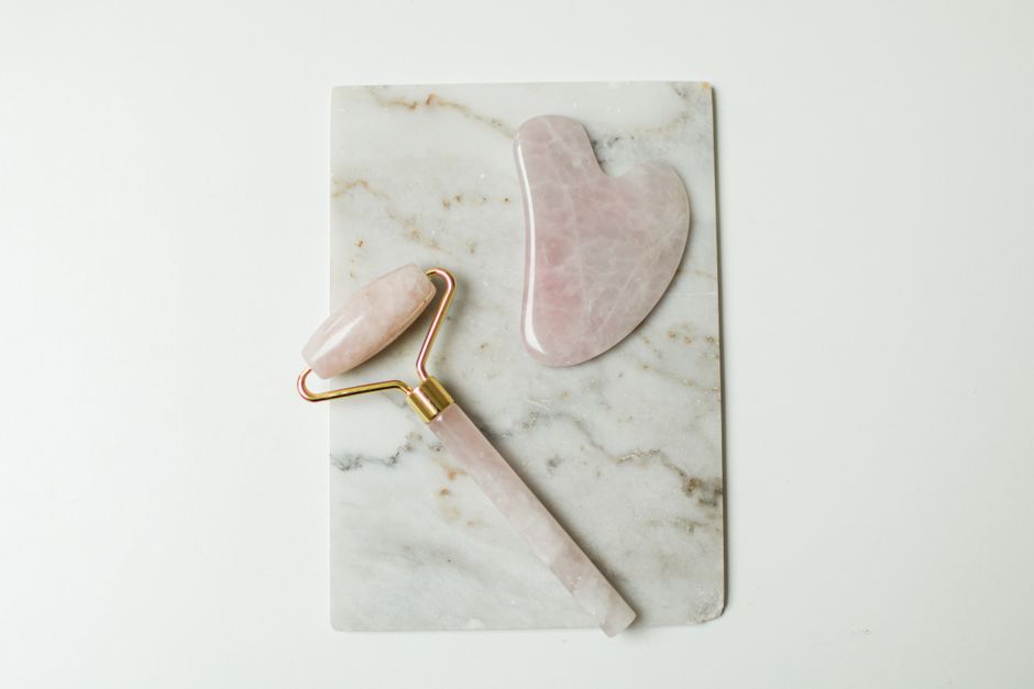 A rose quartz gua sha stone and roller on marble, the tool category Bonsep's rolling-ball serum applicator borrows from. — Photo by Cup of Couple on Pexels