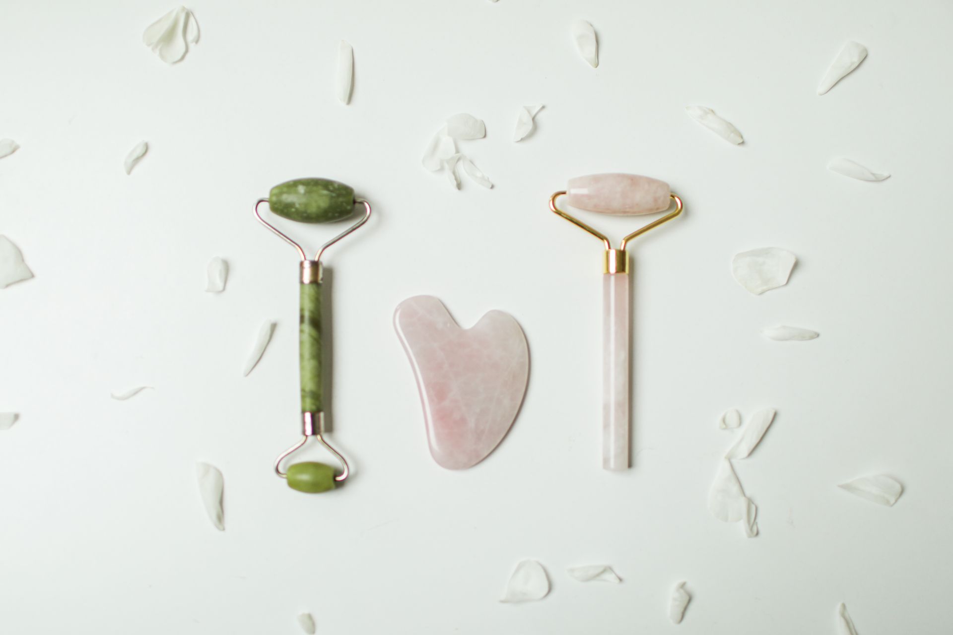Stylish jade rollers and gua sha tools arranged on a white background, ideal for skincare routines.