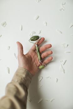 Close-up of a hand holding a jade roller, ideal for facial care and self-care routines.