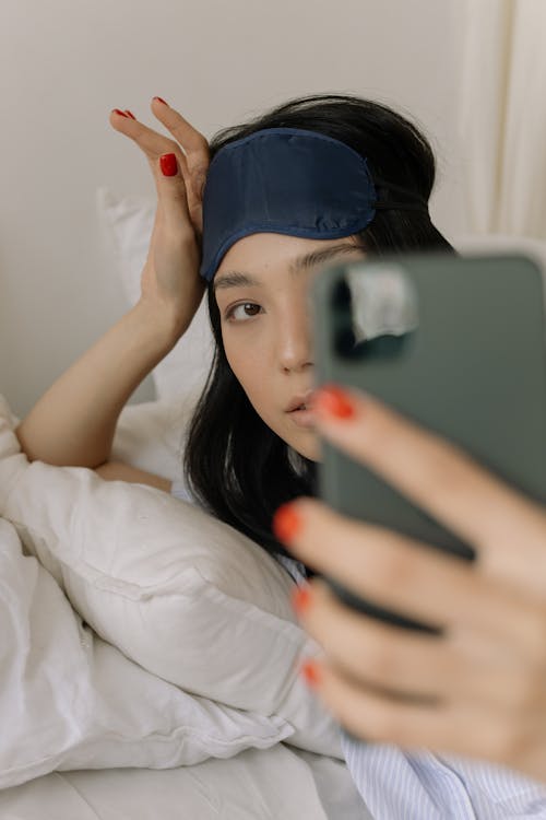 Free Young Woman Lying in Bed and Taking a Selfie  Stock Photo