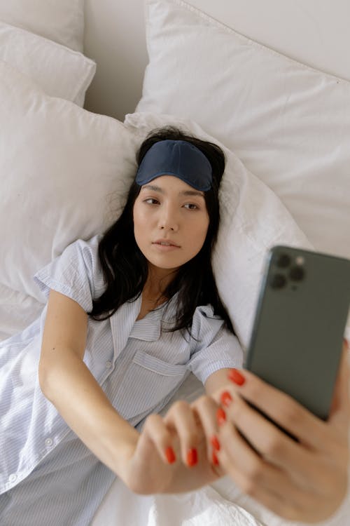 Free Young Woman Lying in Bed and Taking a Selfie Stock Photo