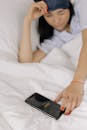 Woman Reaching Cellphone in Bed