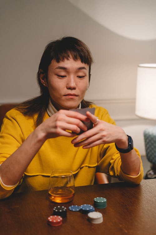 Woman Holding Playing Cards with Poker Chips on Table