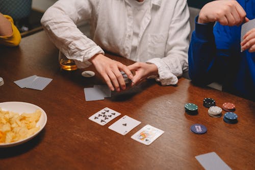 Person in White Dress Shirt Sitting Beside Brown Wooden Table