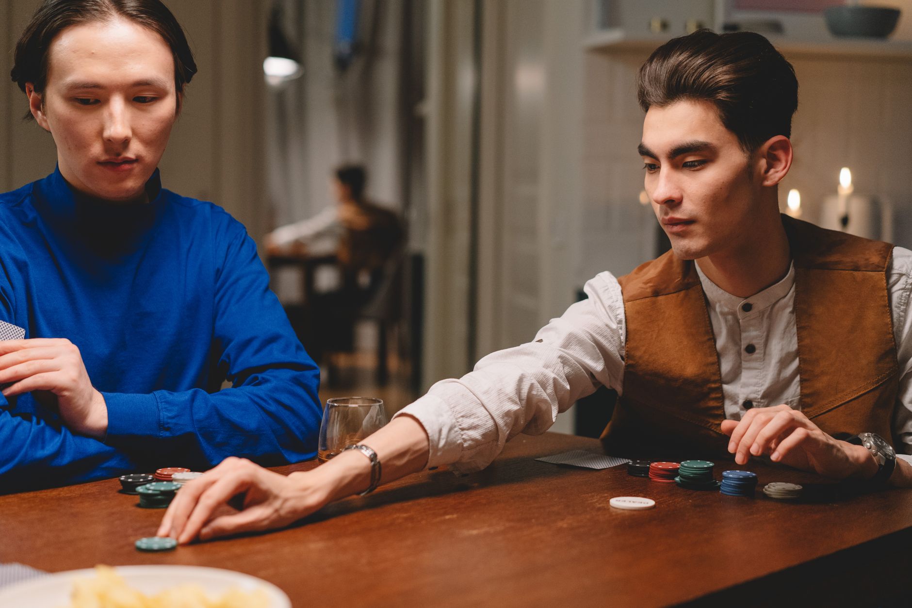 players comparing three patti cards under warm indoor lighting, chips carefully stacked near the dealer