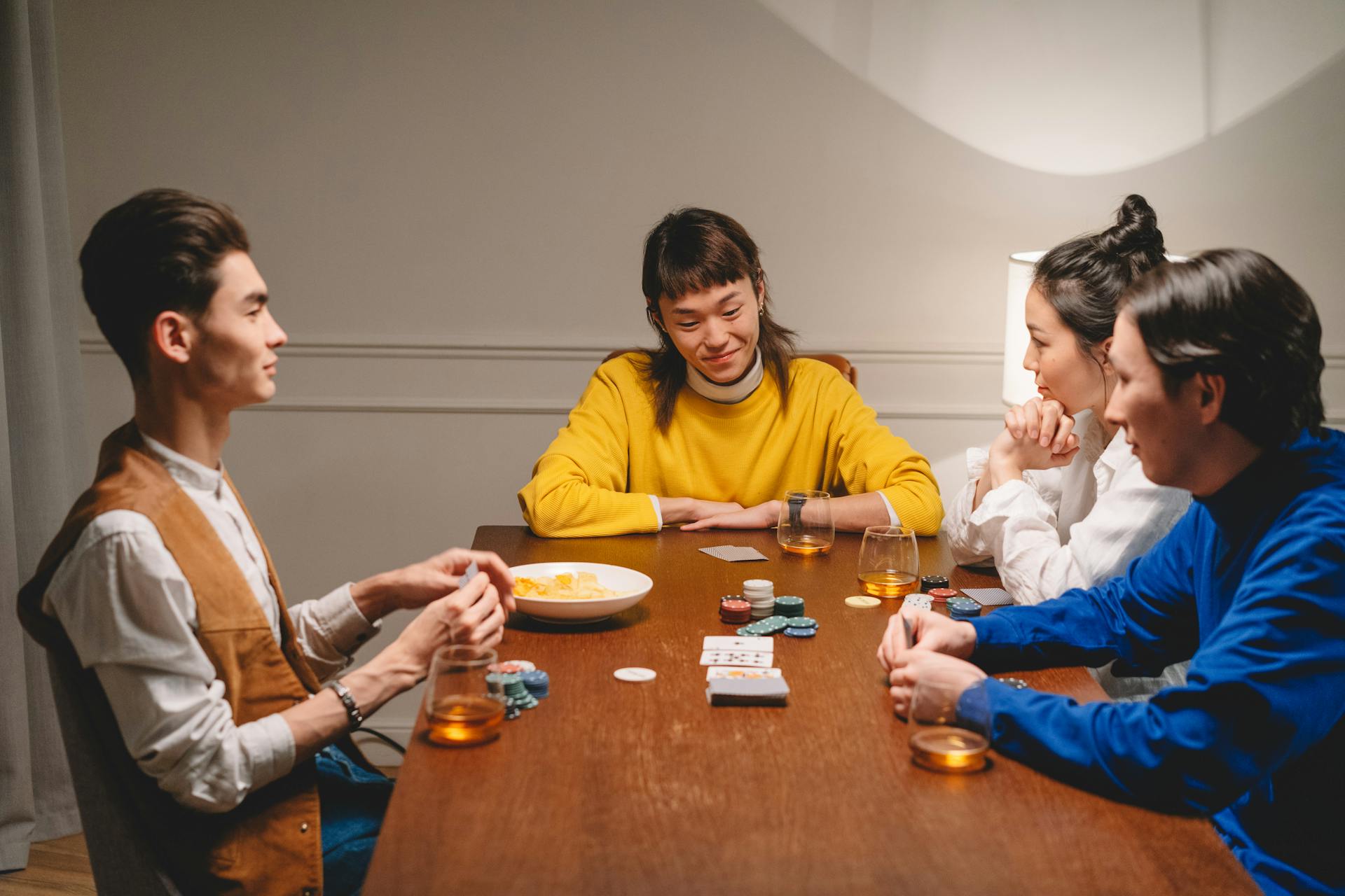 A diverse group of friends playing poker with chips and cards in an indoor setting, enjoying the game.