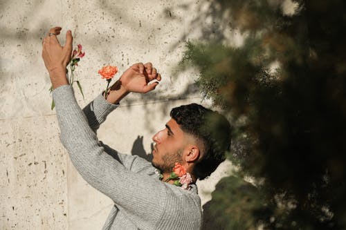 Man in Gray Sweatshirt Posing with Carnation Flowers