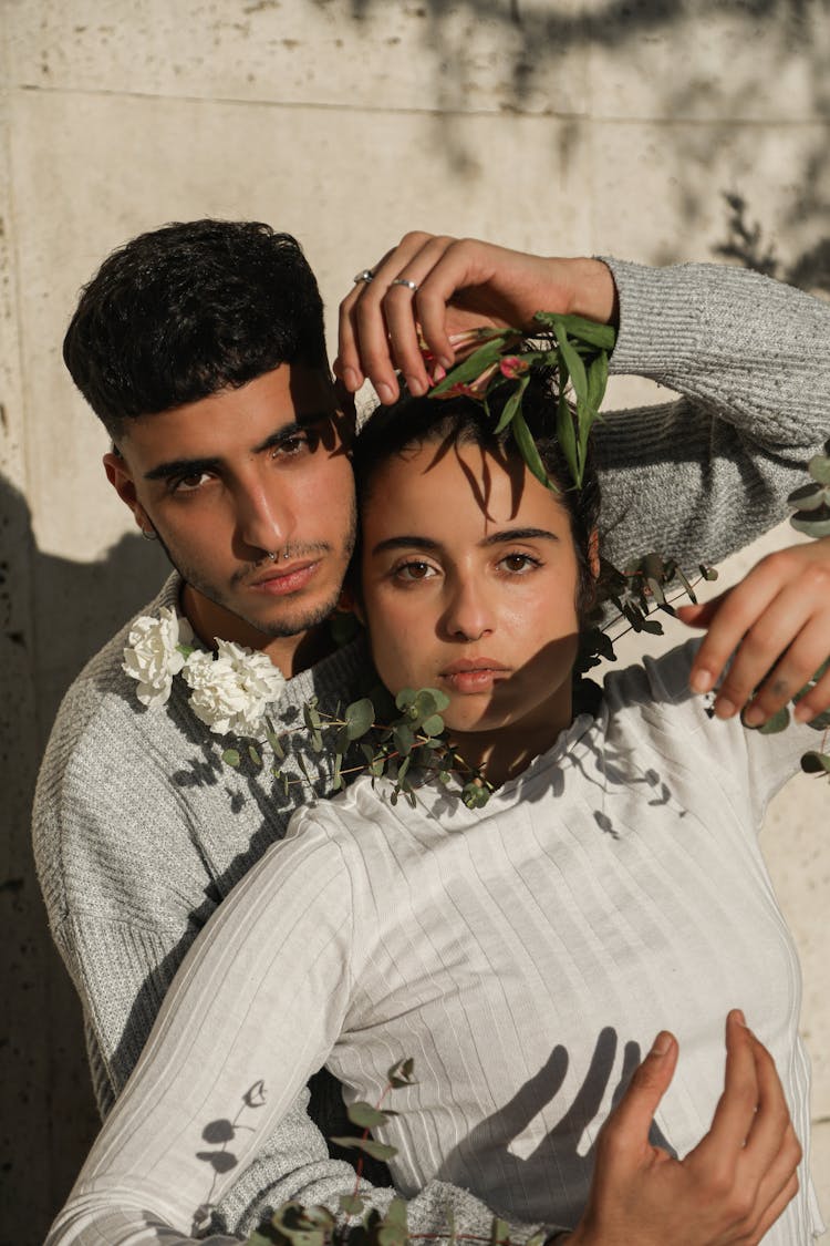 Young Man And Woman Sitting Outside In Sunlight And Embracing 