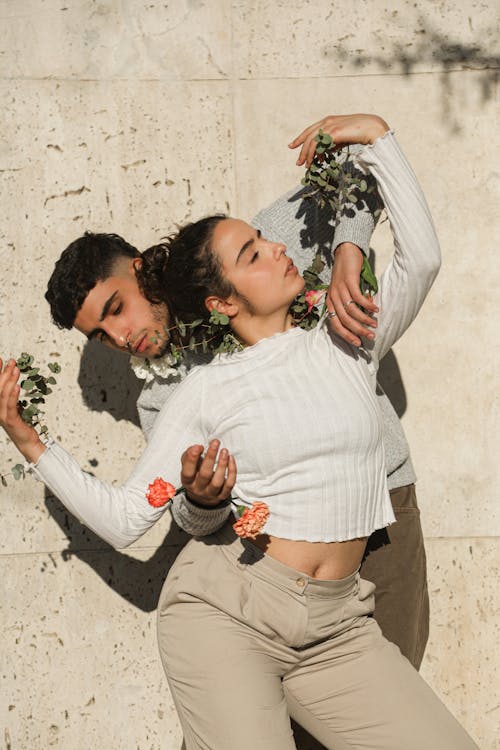 A Couple Standing Together while Holding Green Plants