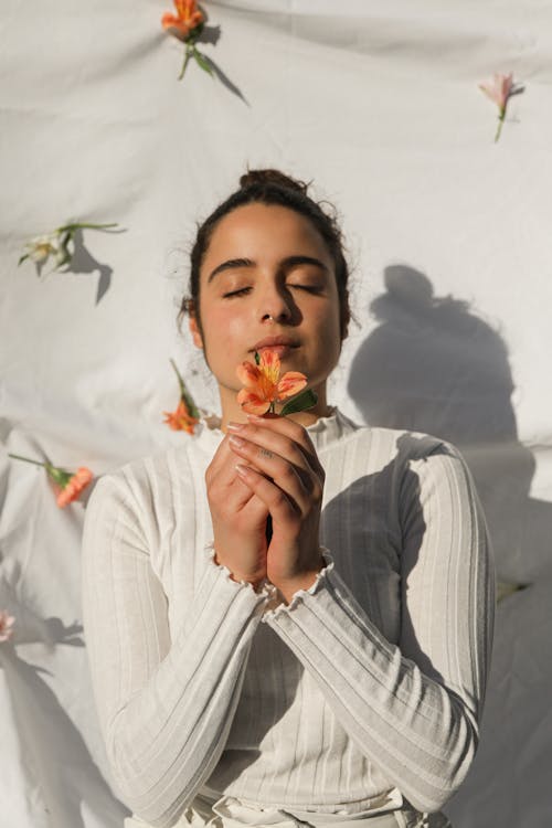 Woman in White Sweater Holding a Flower