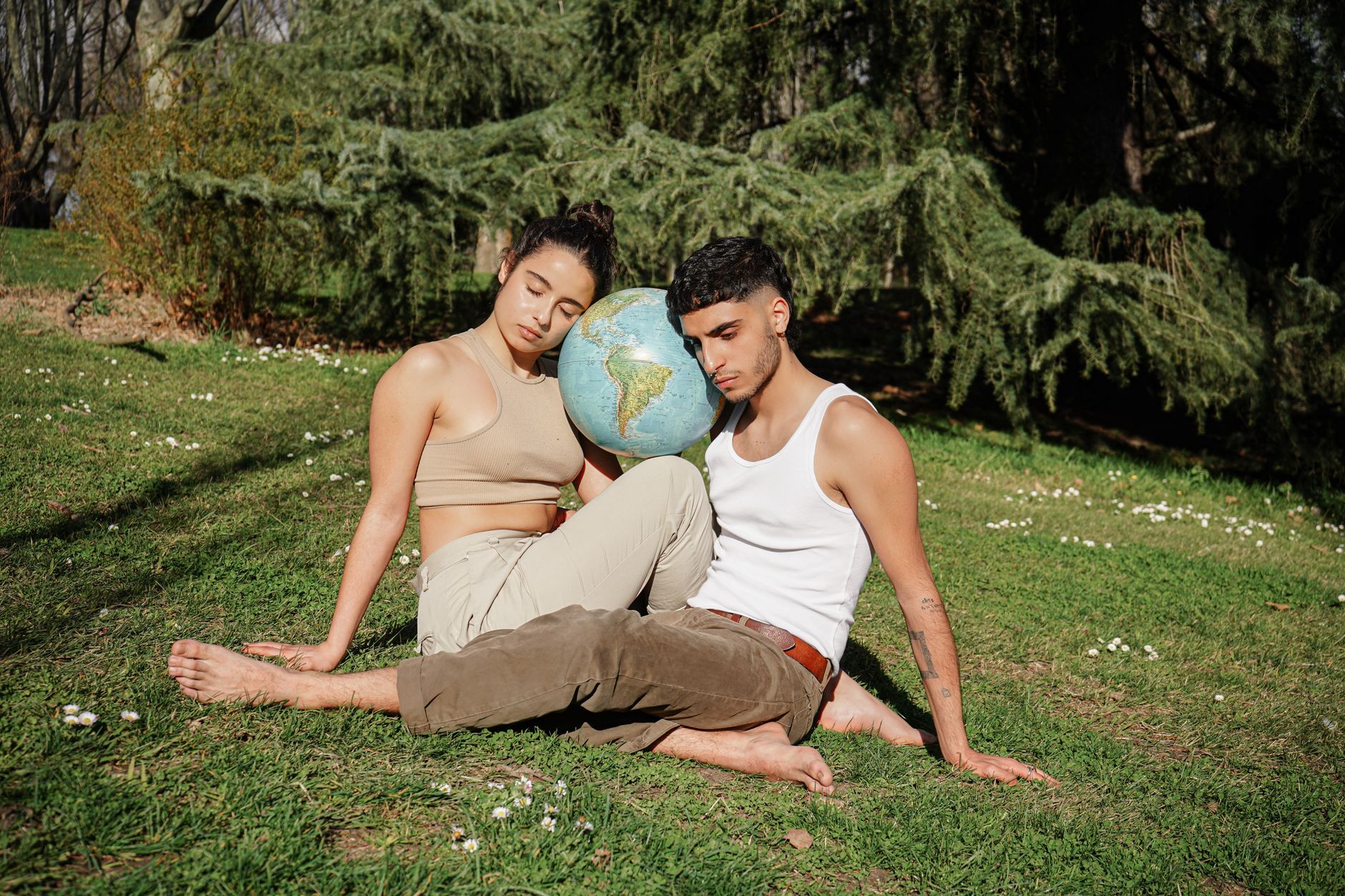A couple sitting in a park, embracing eco-consciousness with a globe symbolizing unity with nature.