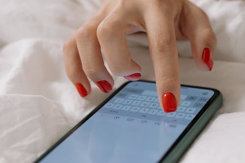Free Hand of a Person With Manicured Nails on a Smartphone Screen Stock Photo