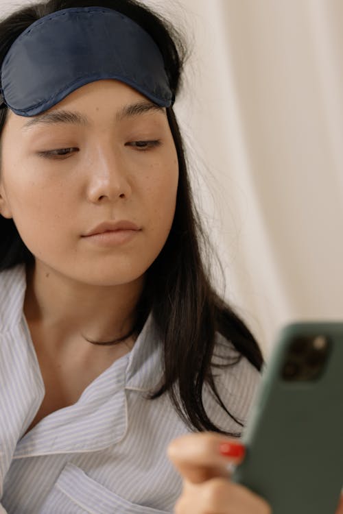 Free Woman with Sleep Mask Looking at the Phone Stock Photo