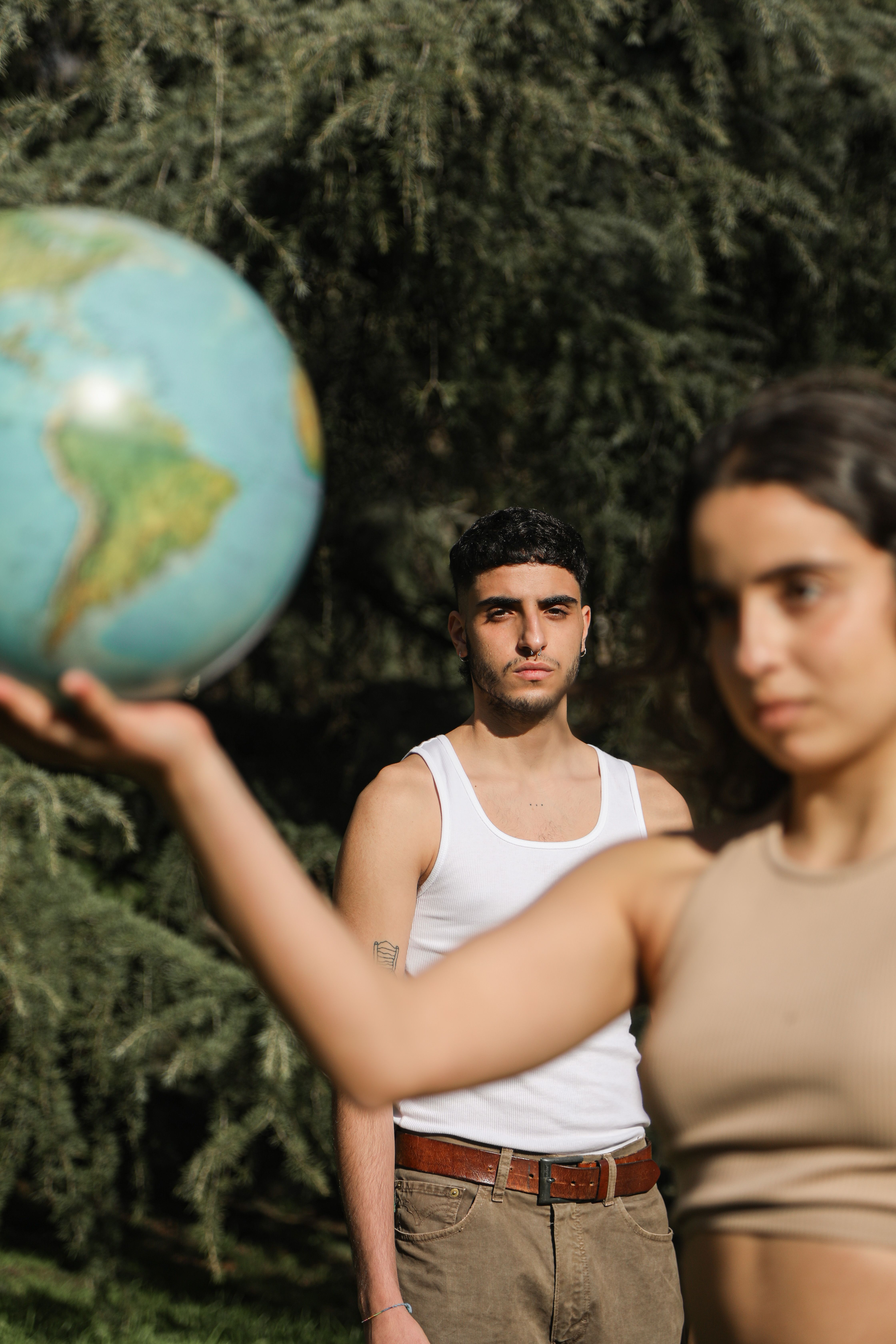 A man and woman holding a globe in a forest, highlighting environmental awareness