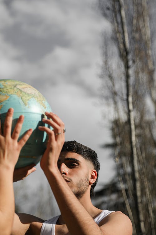 Free A Man Holding a Globe with Another Person Stock Photo