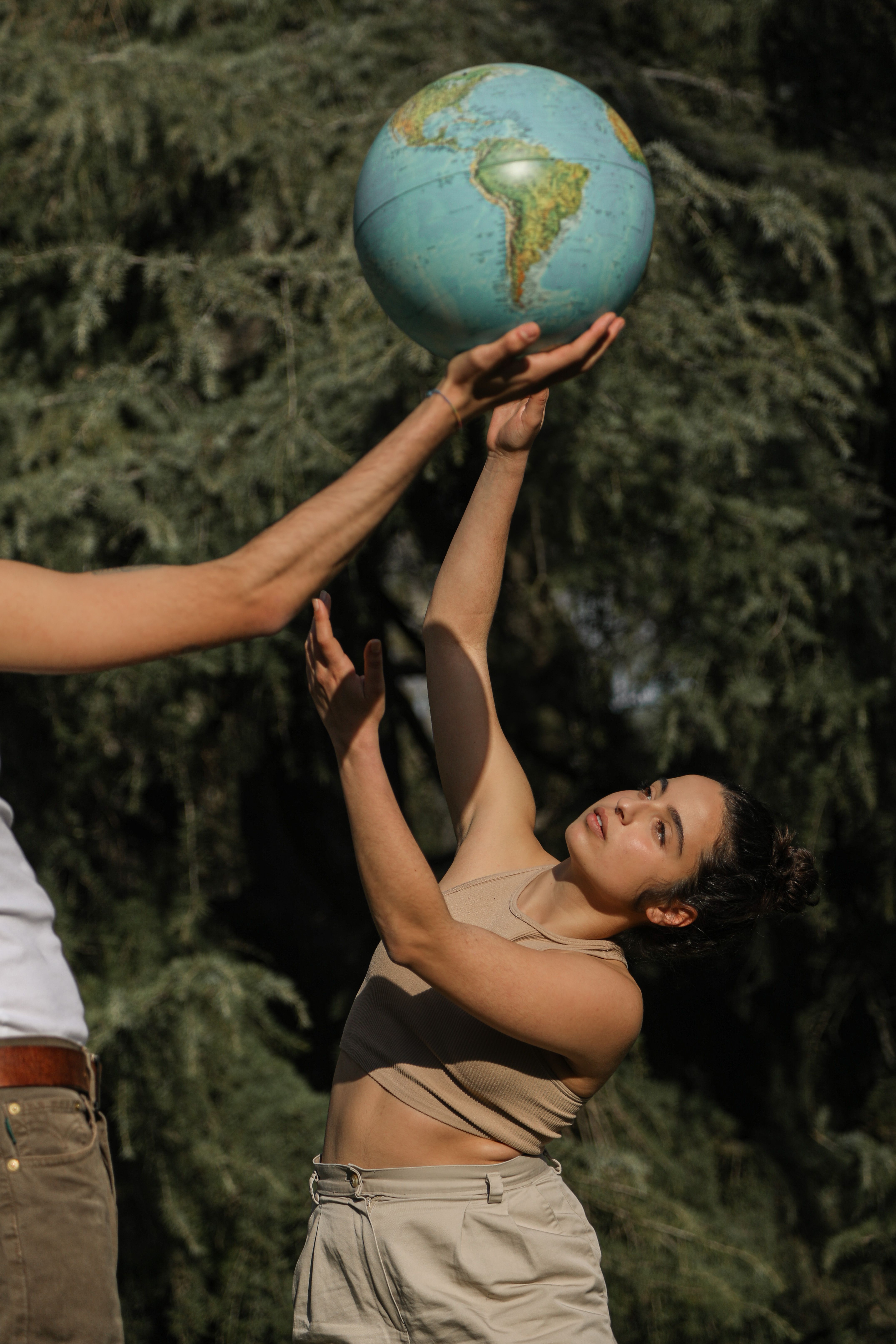 Woman outdoors reaching for a globe, symbolizing environmental awareness.