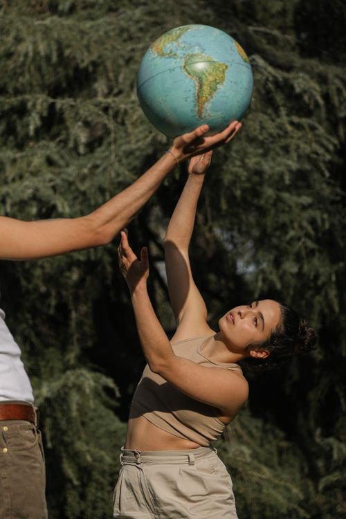 Free Woman outdoors reaching for a globe, symbolizing environmental awareness. Stock Photo