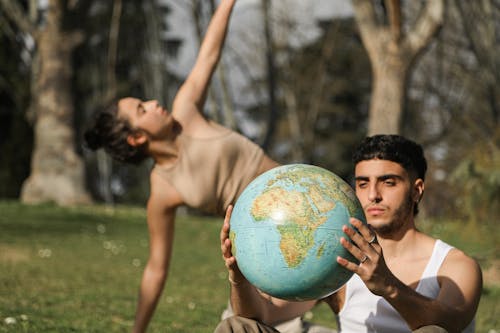 Free Man in White Tank Top Holding a Globe Beside a Woman  Stock Photo