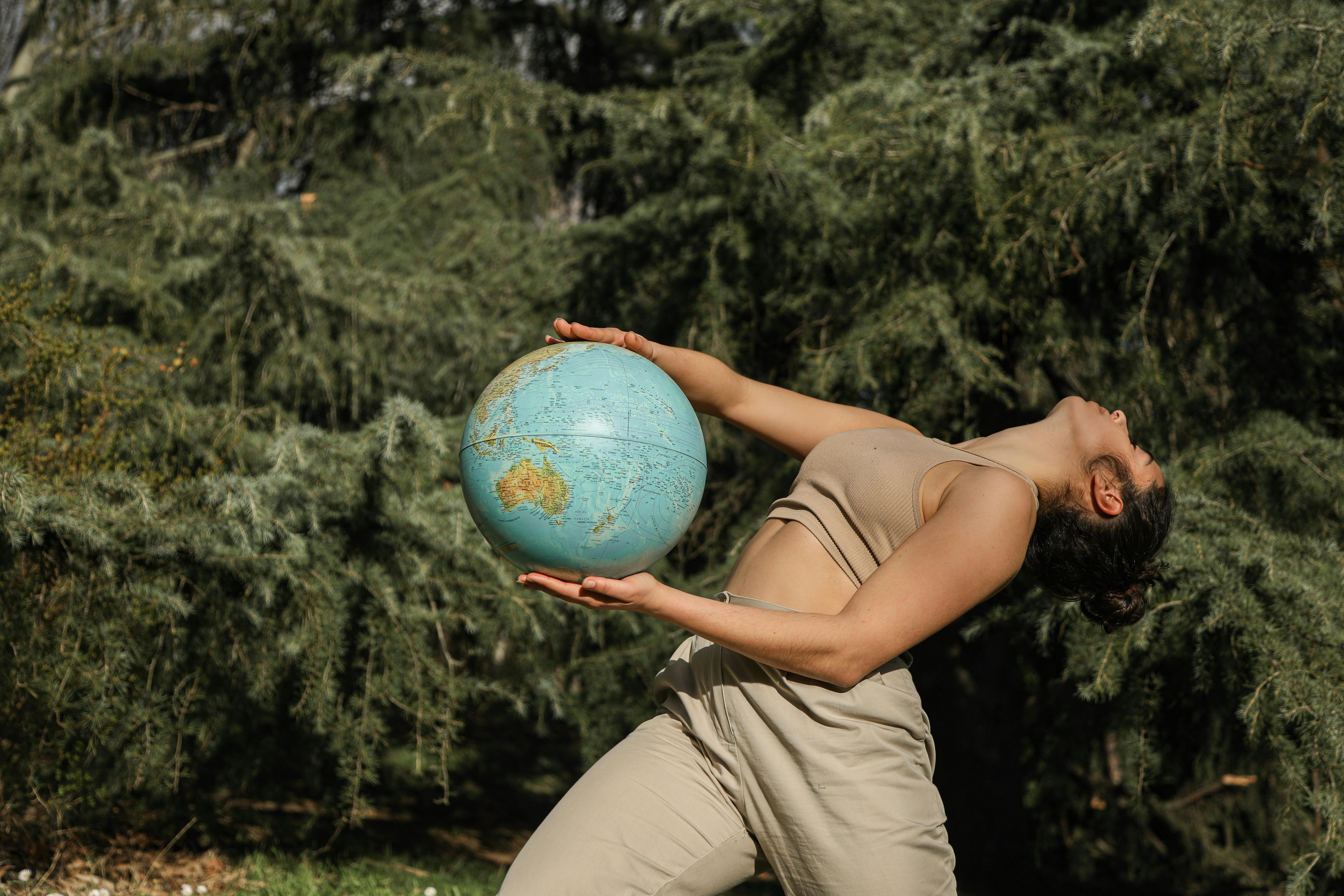 woman in brown tank top and brown pants holding a globe