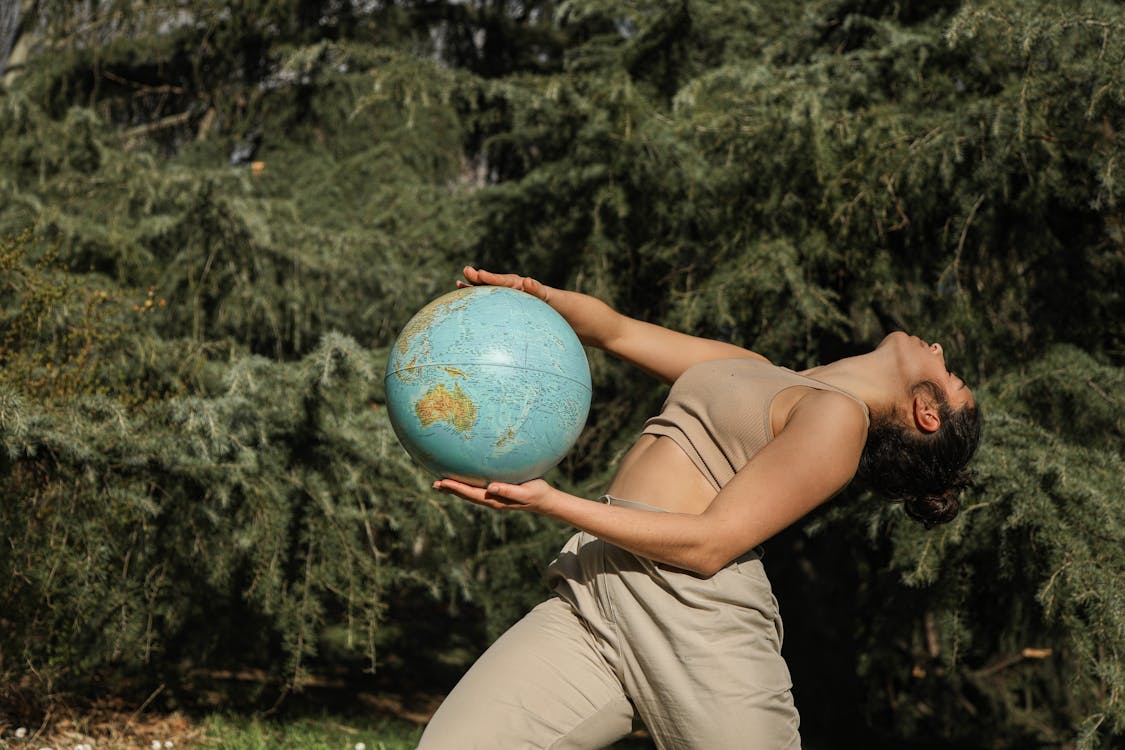 Woman in Brown Tank Top and Brown Pants Holding a Globe