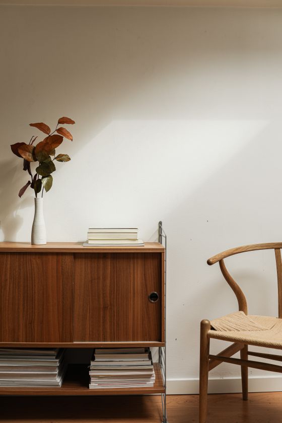 Sunlit room with a walnut sideboard and a woven chair, photo by Cup of Couple on Pexels