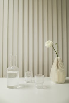 Minimalist decor featuring a ceramic vase and glassware on a clean table in a serene setting.