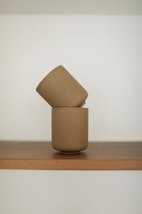 Free Minimalist ceramic cups arranged on a wooden shelf, showcasing modern design. Stock Photo