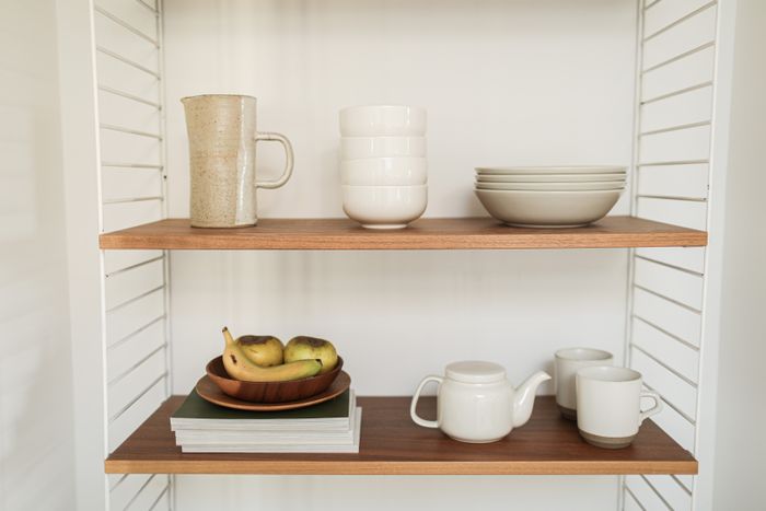 Ceramic dinnerware on a wooden shelf — photo by Cup of Couple on Pexels