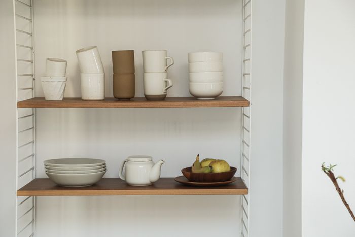 Pottery on open wooden shelves — photo by Cup of Couple on Pexels