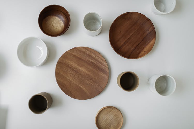 Empty Wooden Plates And Ceramic Cups On White Surface