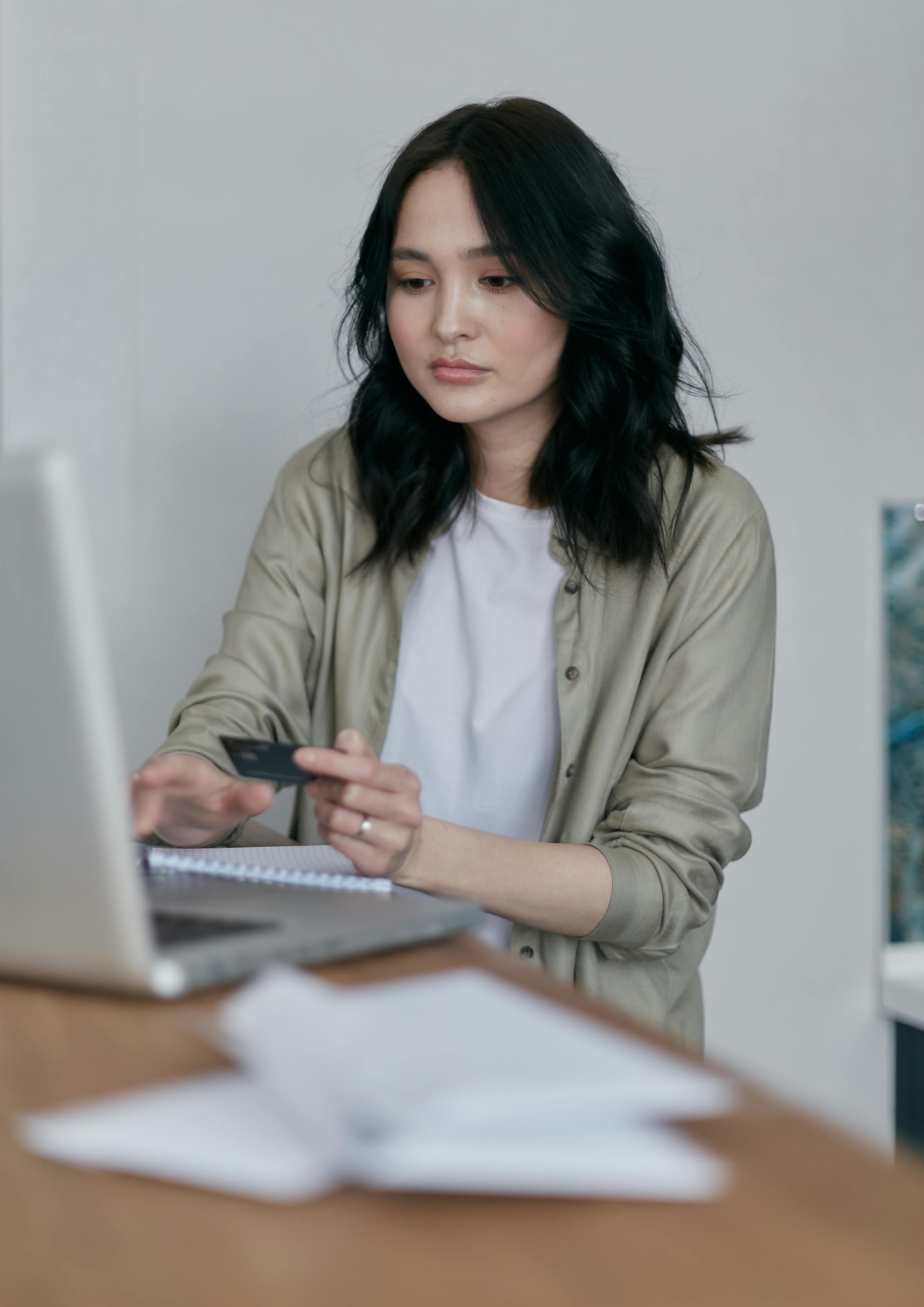 a woman holding a credit card using a laptop