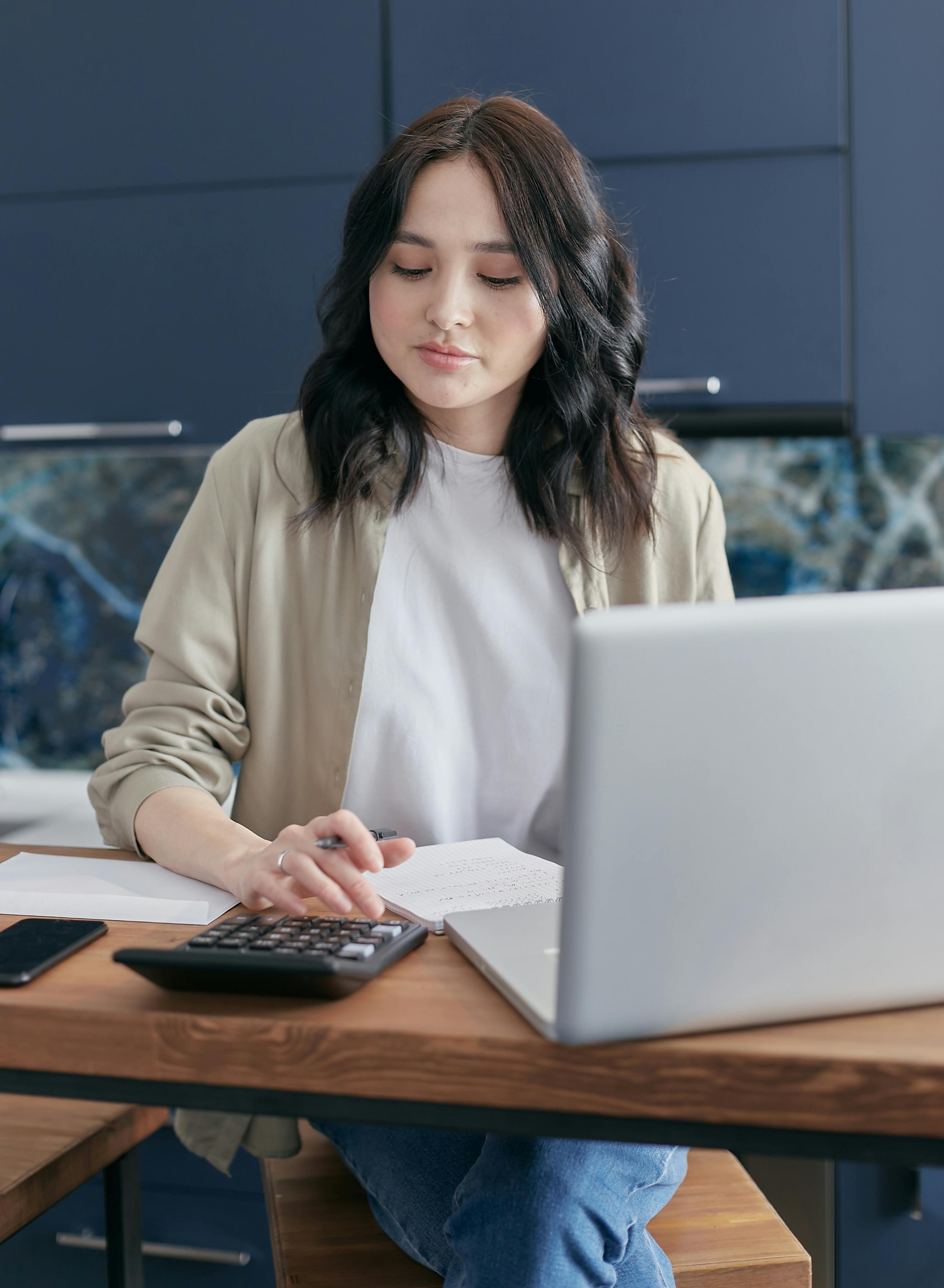 woman in beige blazer holding white laptop computer