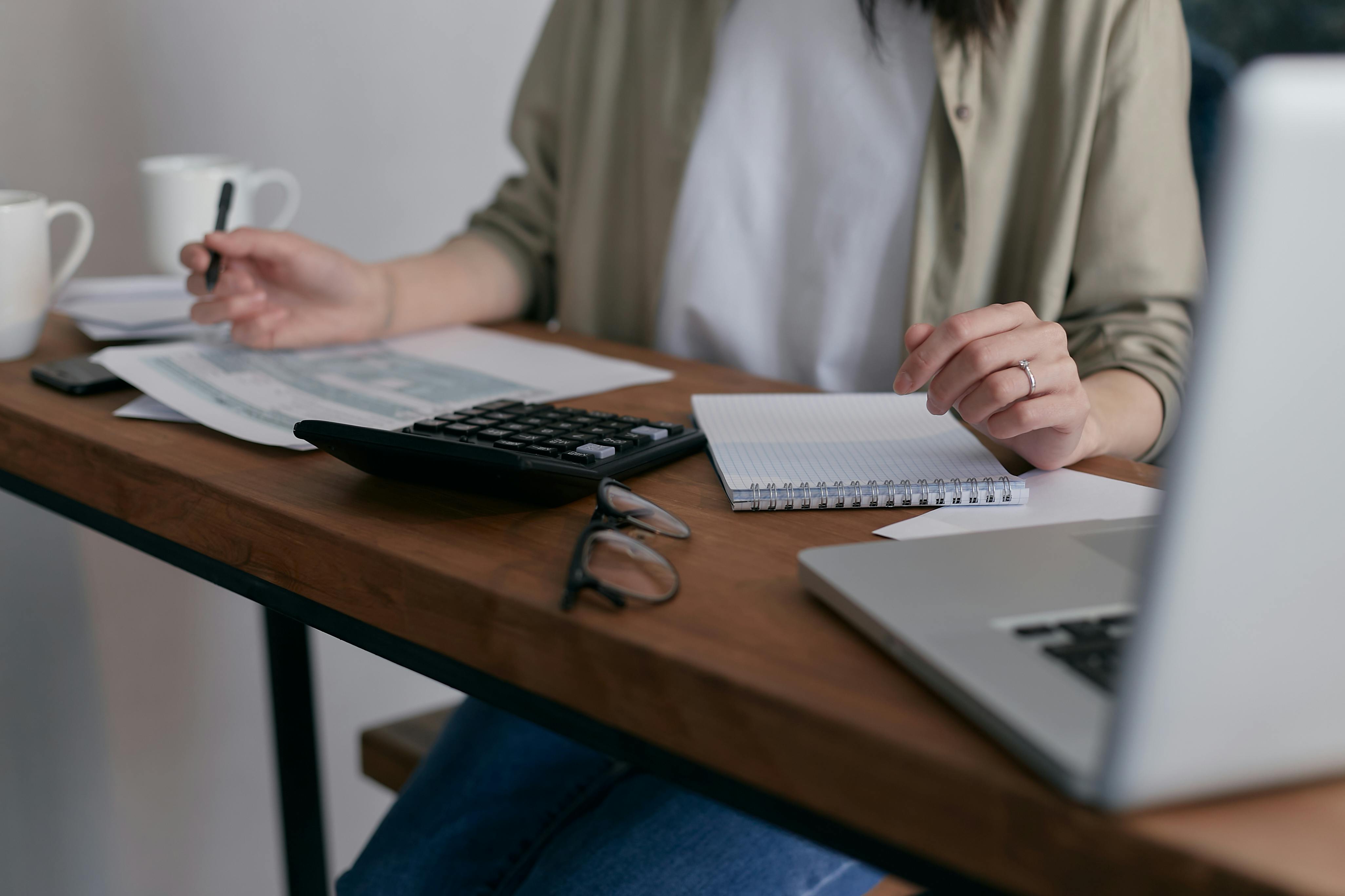 A person sitting on a wooden table and working with a laptop.